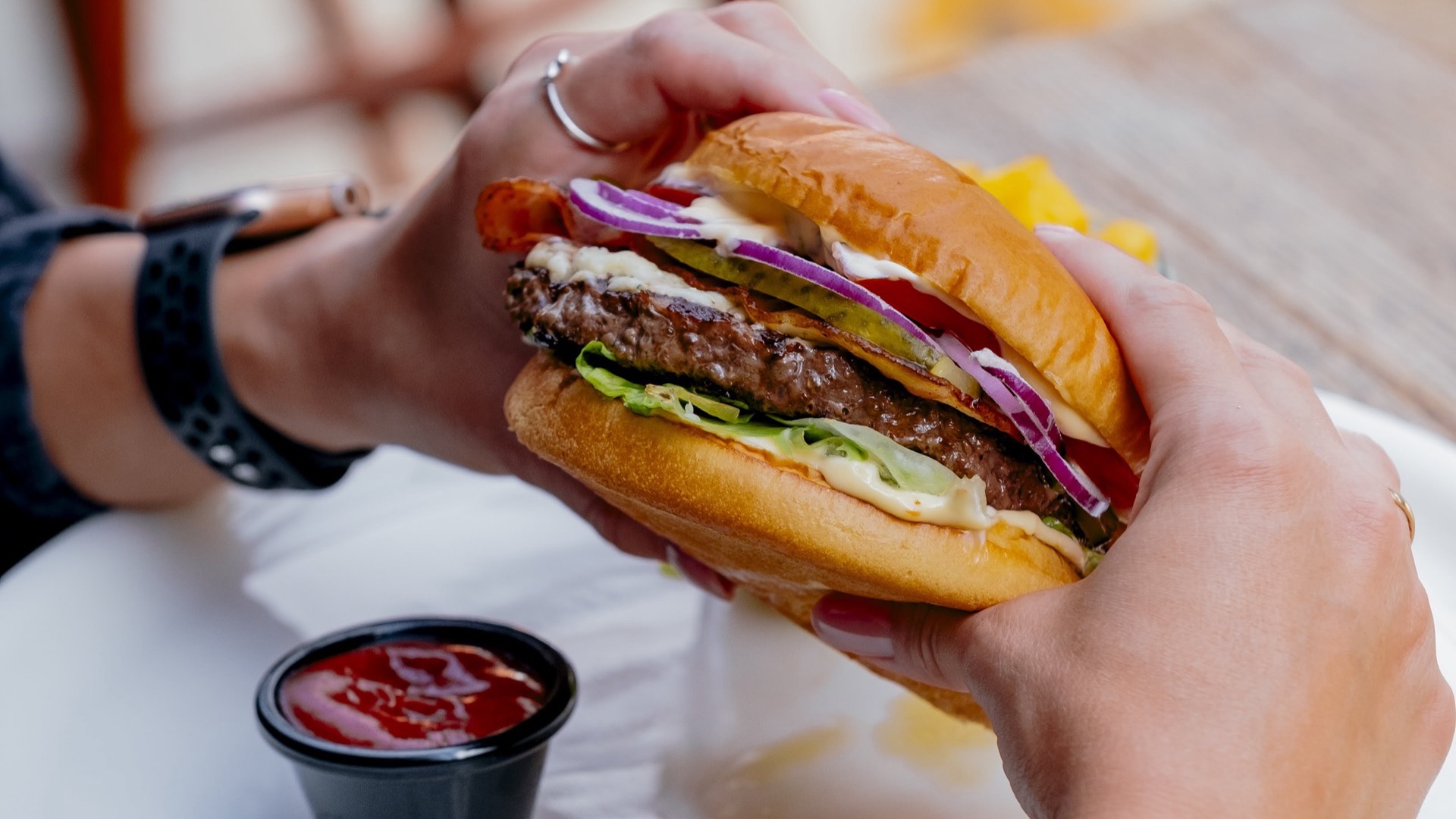 Burger trzymany w dłoni - fotografia kulinarna Warszawa