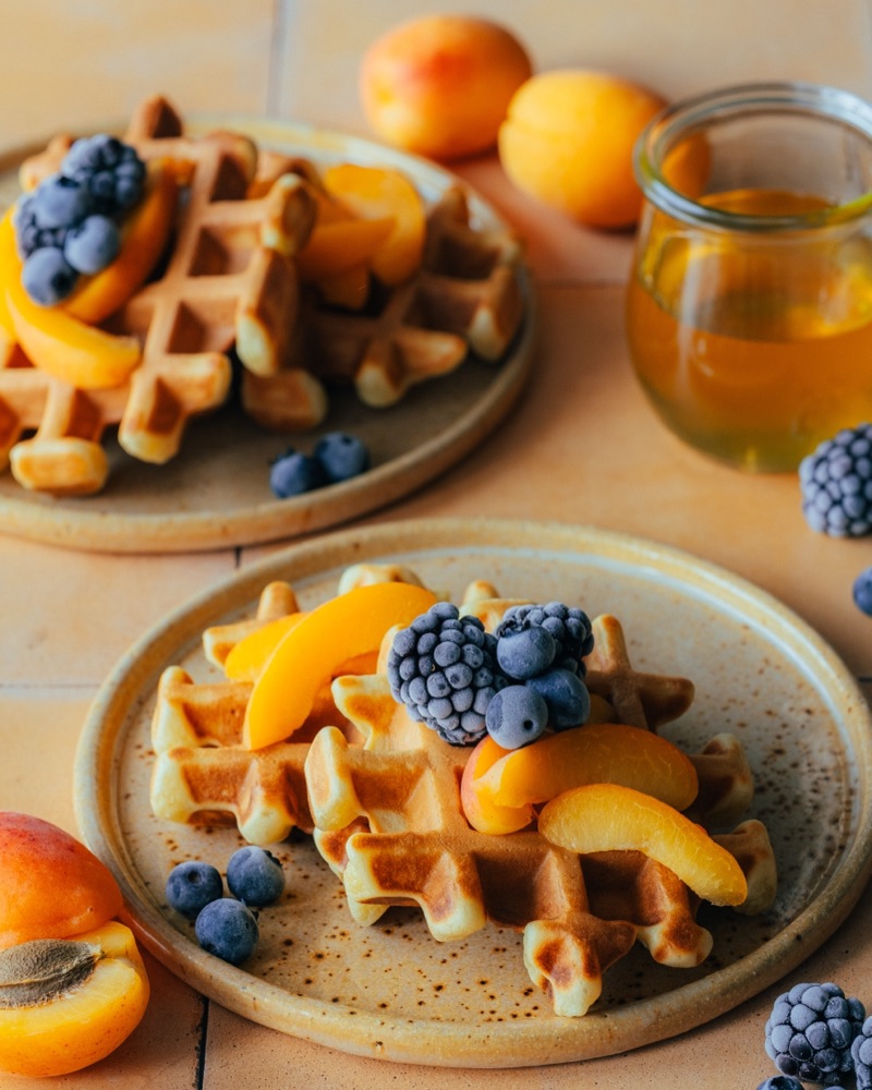 Gofry z morelą i borówkami na pomarańczowym tle - fotografia kulinarna