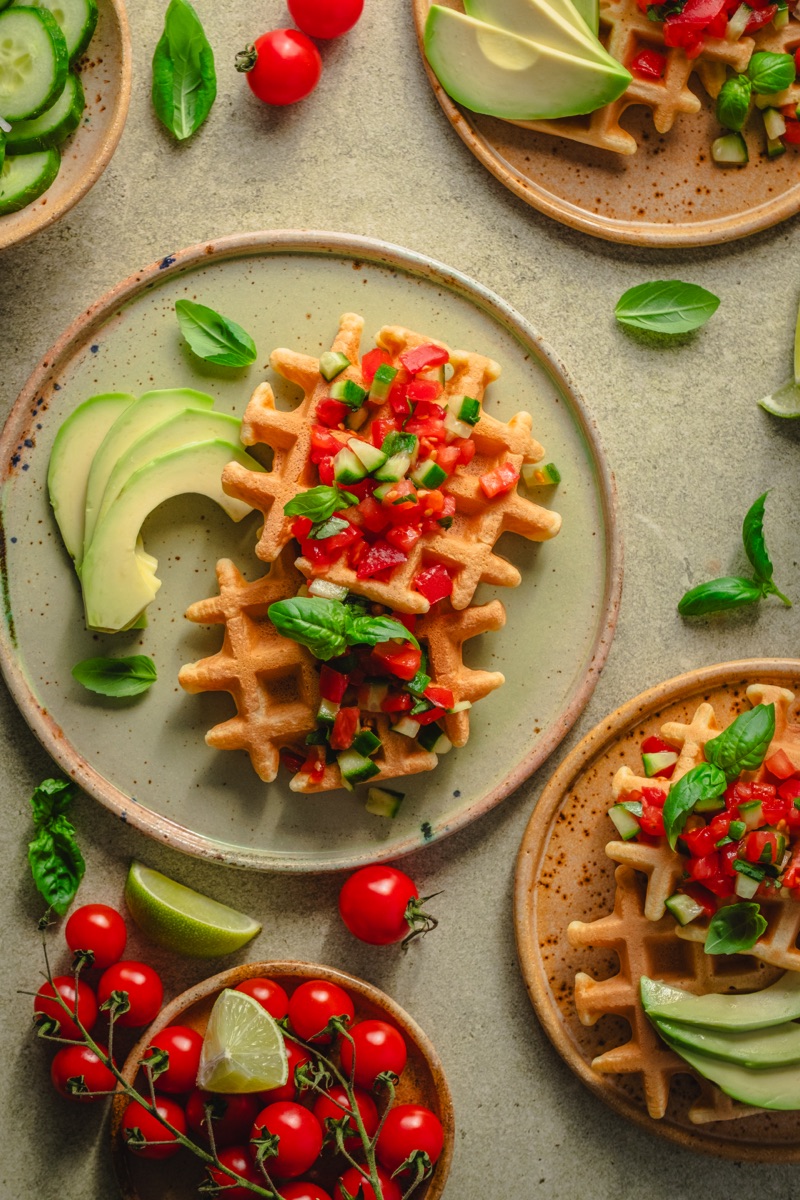 Gofry z awokado i pomidorkami na zielonym tle - stylizacja żywności