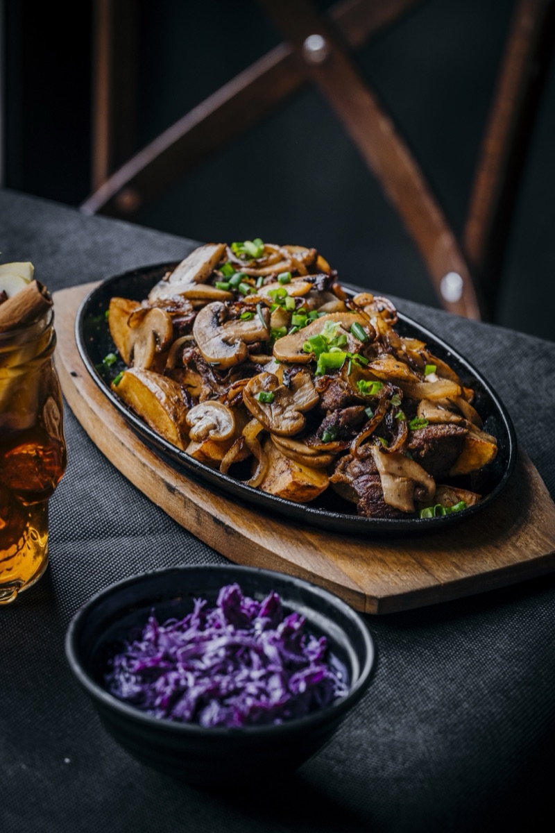 Wątróbka z pieczarkami na czarnym talerzu - fotografia restauracyjna